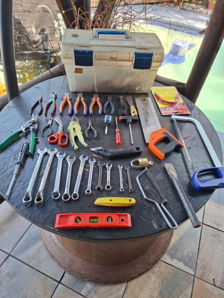 Mixed hand tool collection in plastic toolbox — pliers, spanners, saws, chisels, screws & accessories