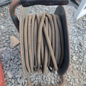 Rusty metal cable reel with coiled cable — single item