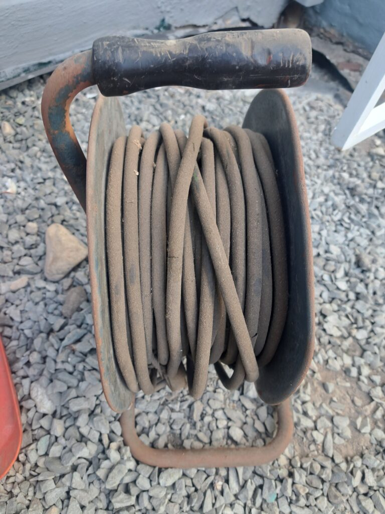 Rusty metal cable reel with coiled cable — single item