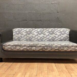 Three-seat patterned grey couch / sofa with visible wear and stains