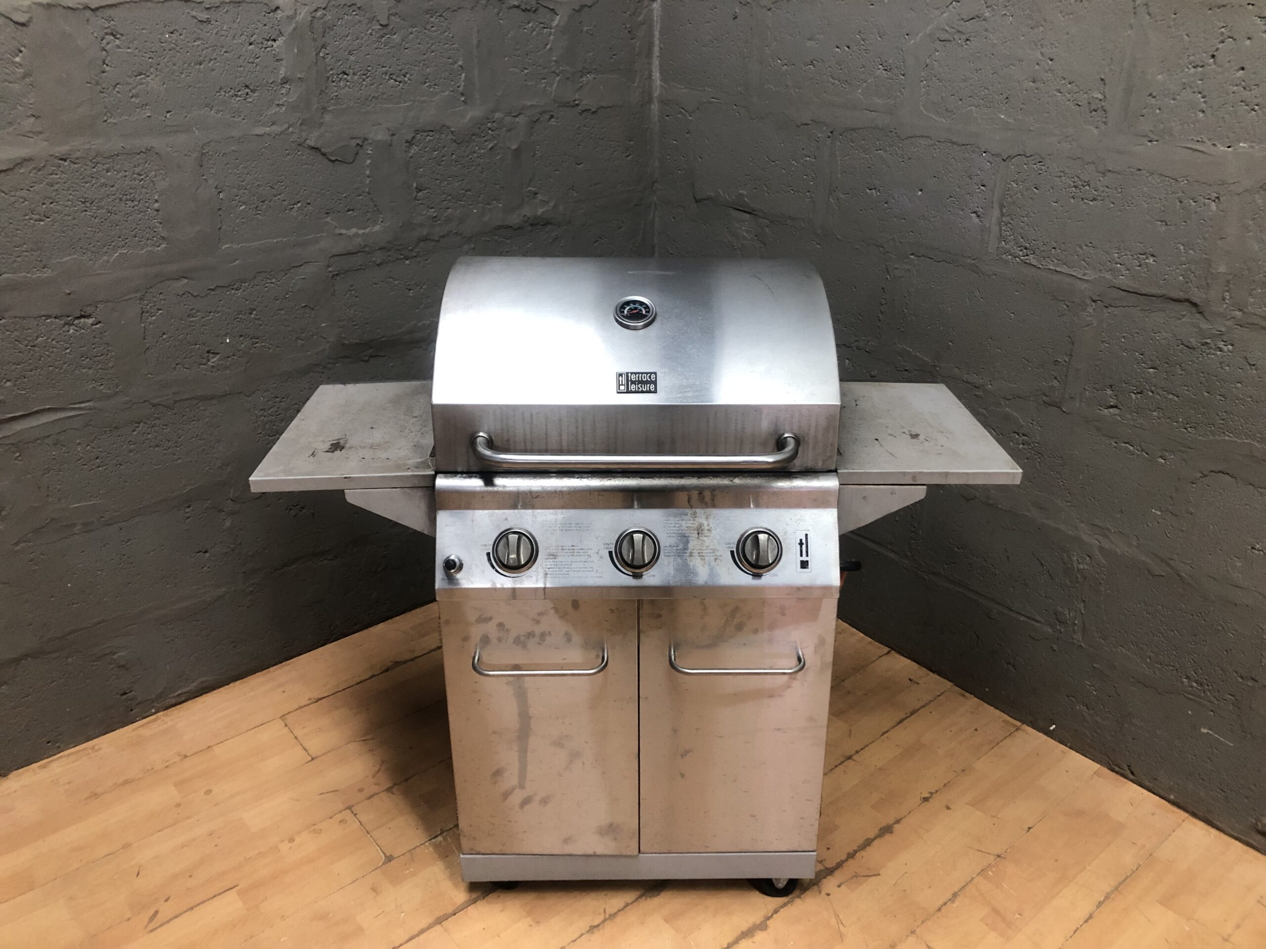 Three-burner freestanding gas barbecue / grill on wheeled cabinet, with side shelves