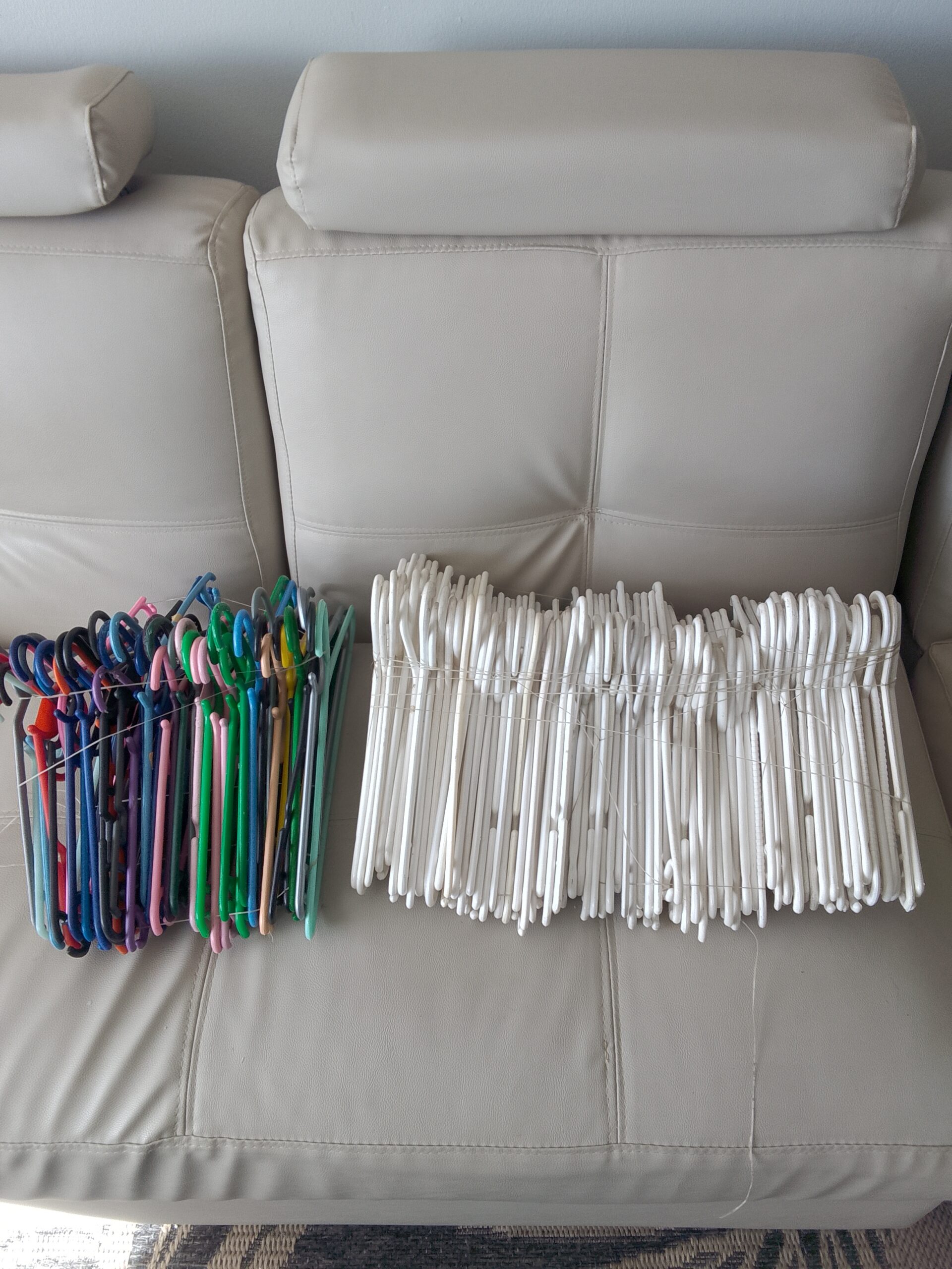 Bulk lot of mixed clothes hangers — predominantly white, assorted colours