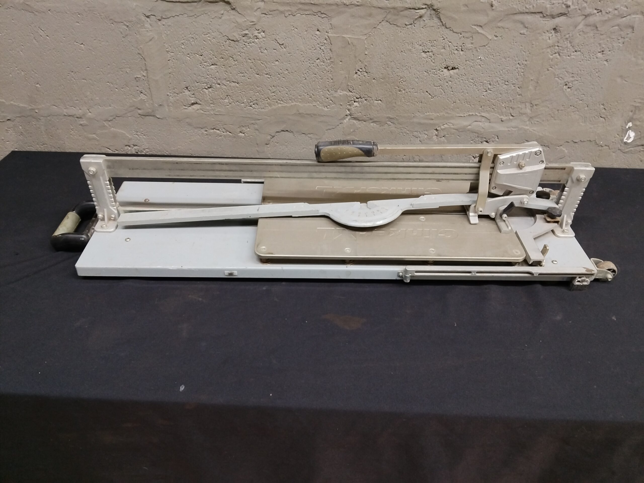 Manual Tile Cutter — 104 x 30 x 29 cm, metal rails, cutting arm, caster wheels