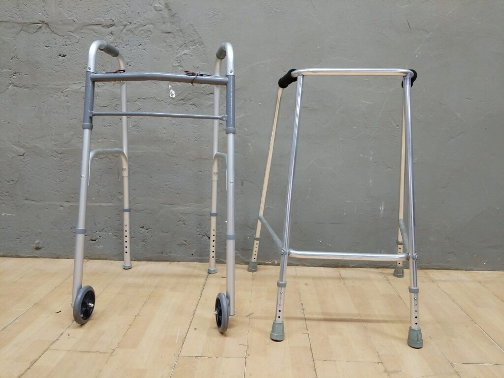 Pair of Metal Walking Frames / Walkers — one with front wheels