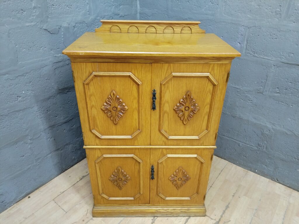 Light oak-coloured wooden cabinet with carved panels & internal shelf