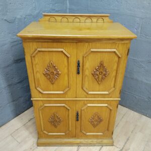 Light oak-coloured wooden cabinet with carved panels & internal shelf