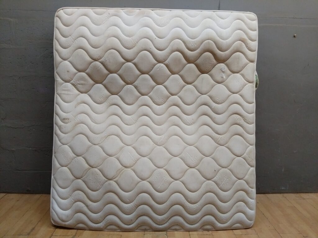 King-size pocketed coil mattress (labelled ‘Pocketed Coil Collection’) — heavily soiled, torn corner, salvage condition