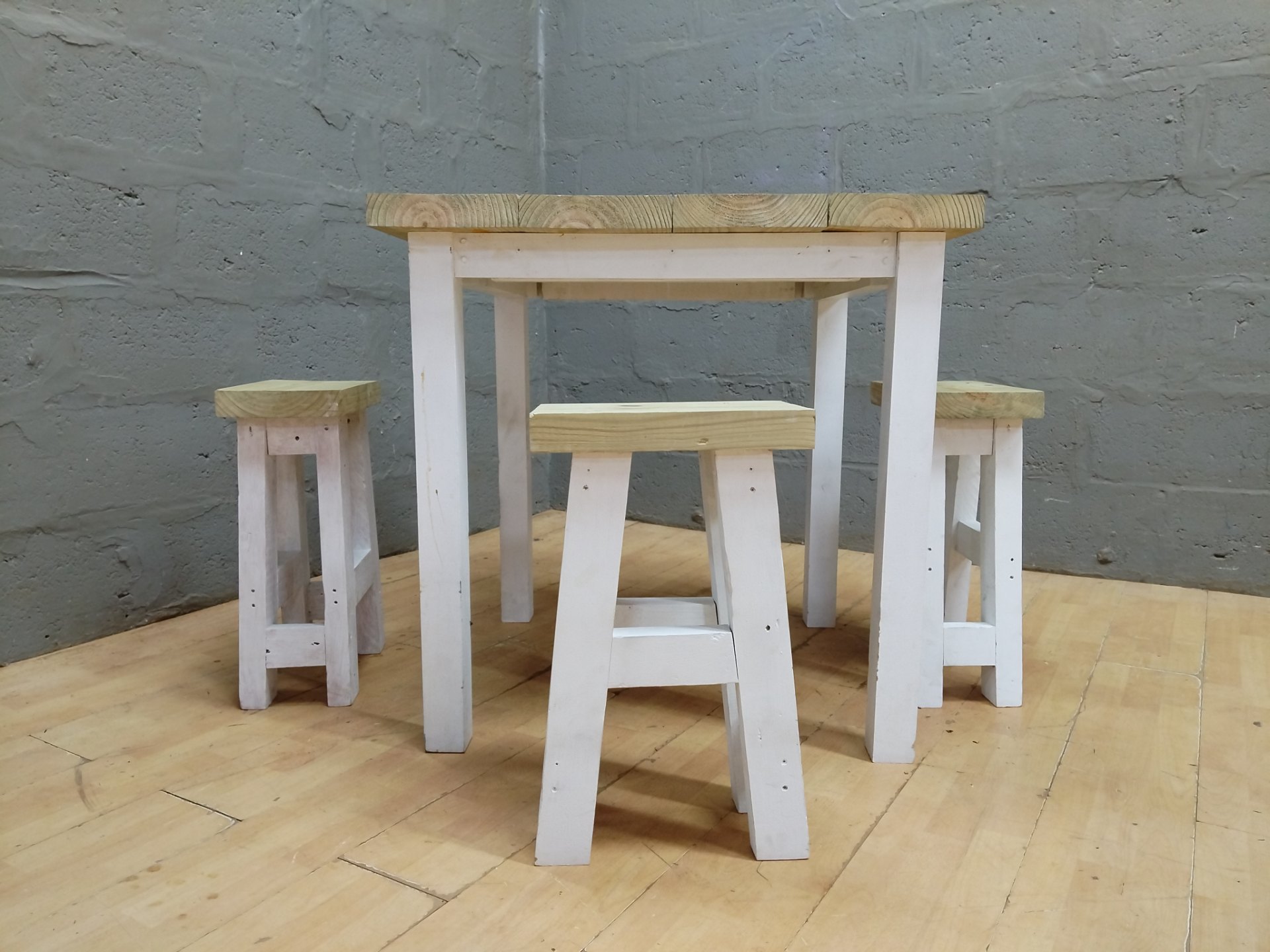 Square wooden table + 3 matching stools — painted legs, raw pine tops (5 pieces)