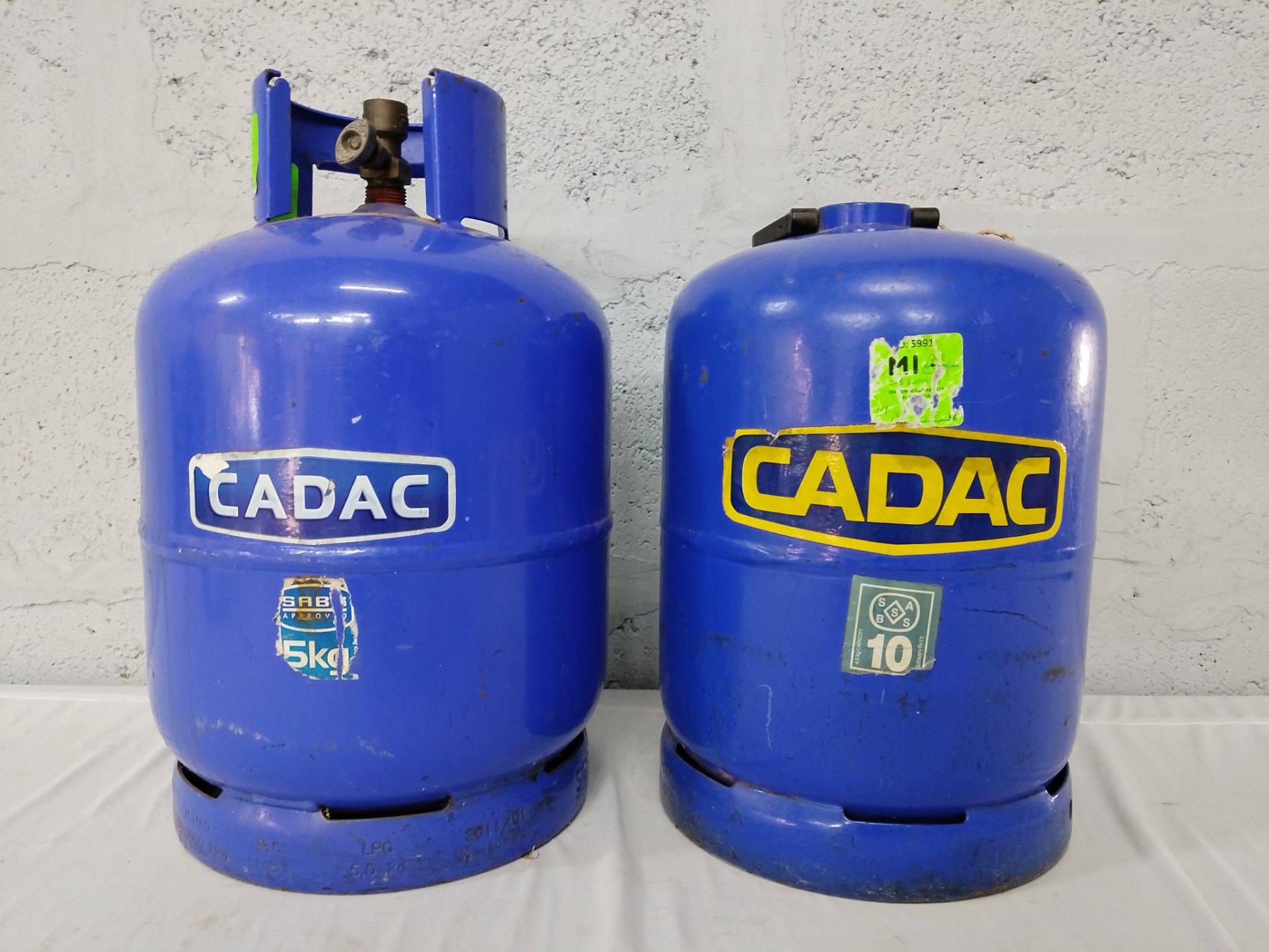 Pair of used CADAC camping gas cylinders — blue (stickers suggest 5kg + 10kg), empty/inspected
