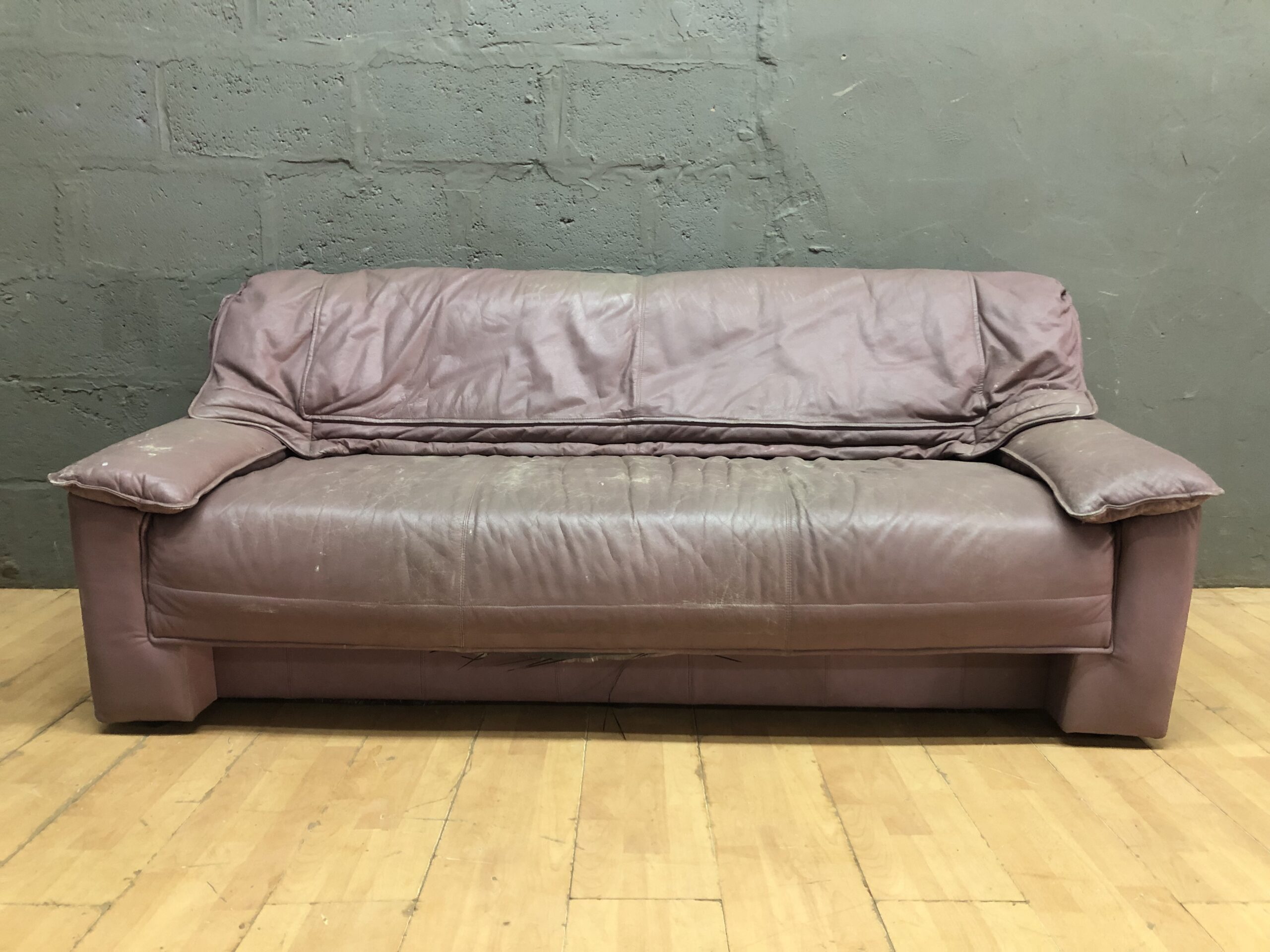 Three-seat brown/plum sofa — heavy surface wear, used