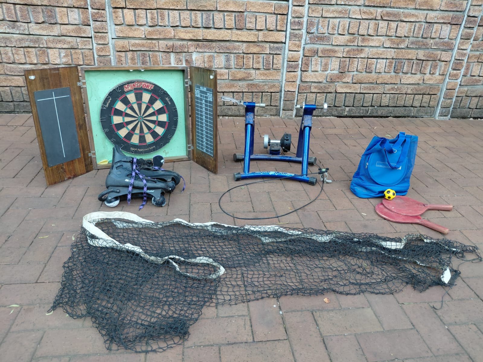 Mixed sports lot — Cyclo-trainer (motorised, worked last time), dartboard cabinet, RollerBall skates, net & paddles