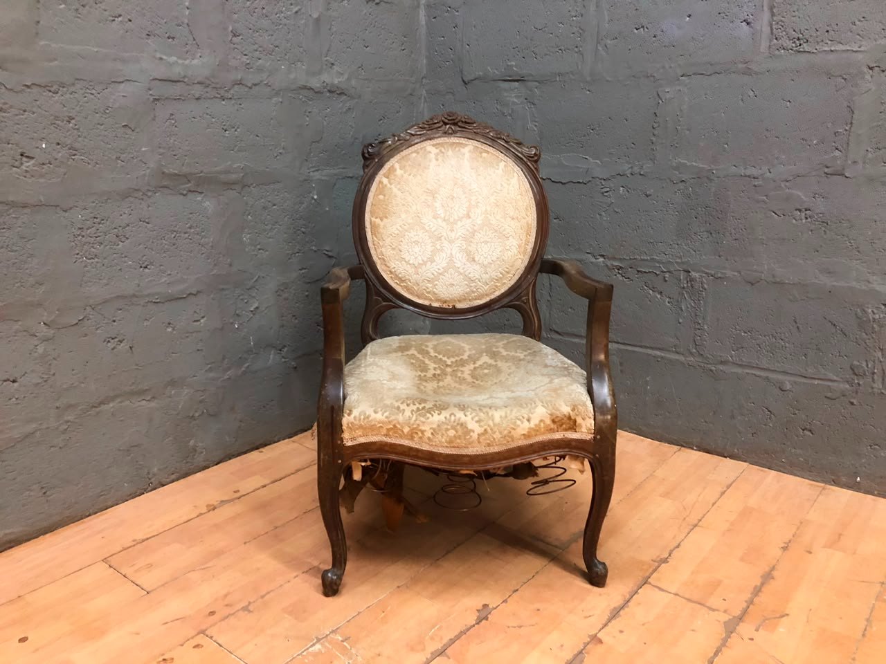 Carved wooden upholstered armchair — decorative back, exposed springs, needs restoration