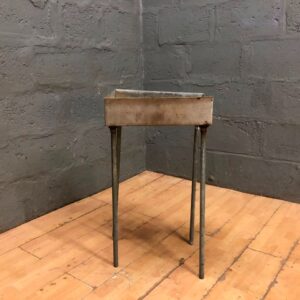 Metal braai on four-leg stand — small industrial-style tray, heavy surface wear, one wobbly leg (44 x 34 x 80cm)