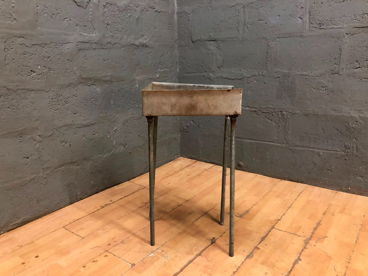 Metal braai on four-leg stand — small industrial-style tray, heavy surface wear, one wobbly leg (44 x 34 x 80cm)