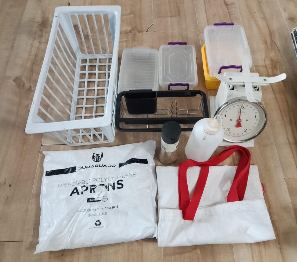 Mixed kitchen & storage lot – plastic crate, tubs, manual scale, cutlery organiser, Duraguard aprons (open pack) & assorted organisers