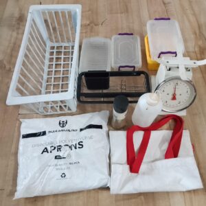 Mixed kitchen & storage lot – plastic crate, tubs, manual scale, cutlery organiser, Duraguard aprons (open pack) & assorted organisers