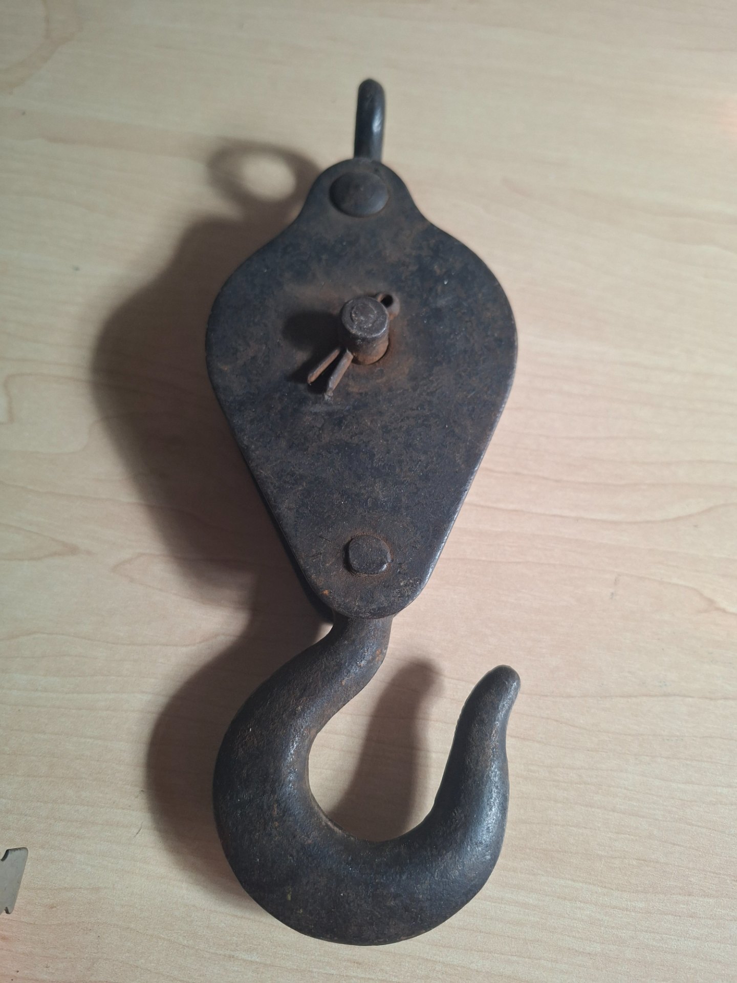 Cast single-sheave pulley block with hook — approx 21cm, heavy surface rust, wheel confirmed to rotate