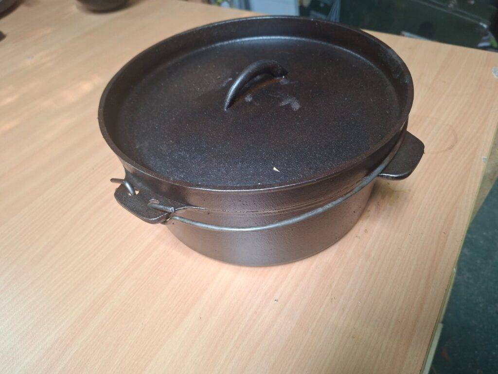 Cast-iron camp pot / Dutch oven with lid — seasoned, approx 27–28 cm