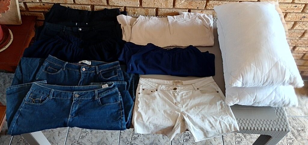 10-piece lot: 8 ladies pants (denim, black, 3/4 & short) + 2 quilted pillows — used, washed, visible marks
