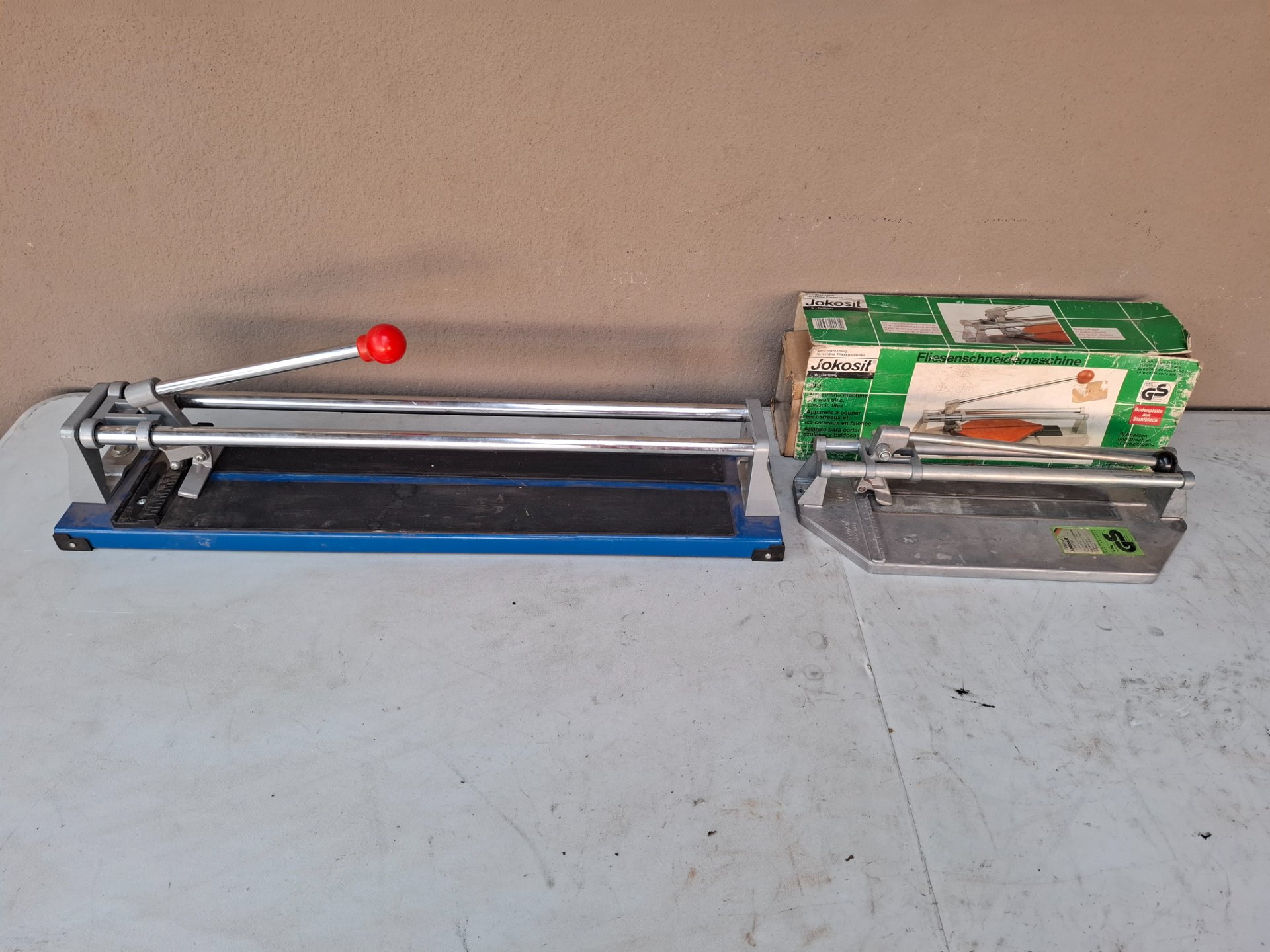 Lot: Two manual tile cutters (long blue cutter + Jokosit boxed cutter) — used, untested