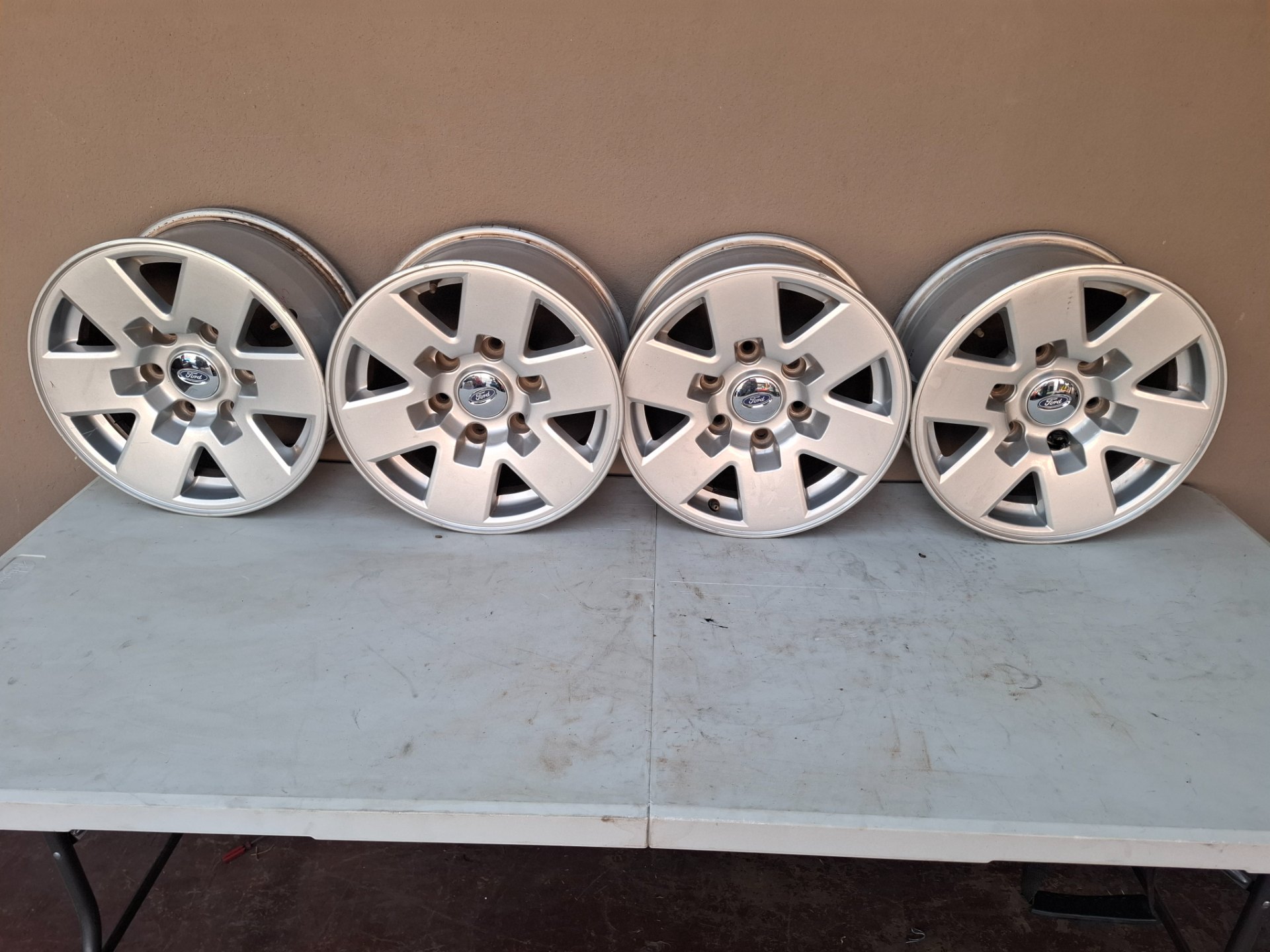 Set of 4 Ford alloy wheels (marked 15x7JJ) with Ford centre caps & valve stems — used, curb rash