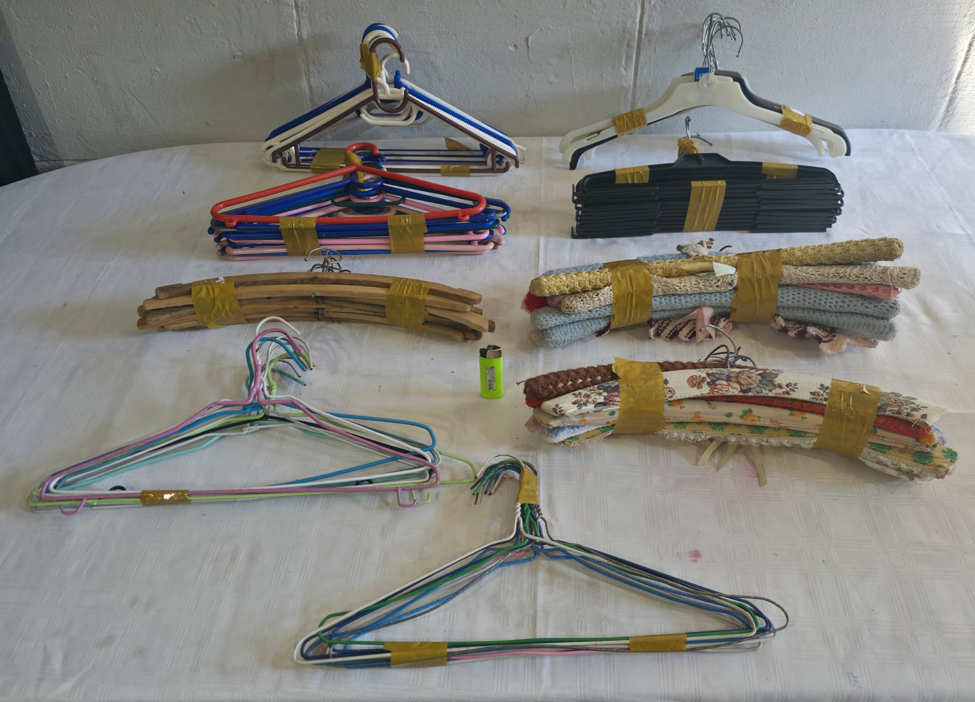 Mixed lot of approx. 90 clothes hangers — plastic, metal, wood, padded/fabric-covered, sold in taped bundles