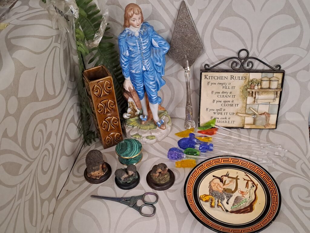 Mixed decorative lot — blue porcelain figure, Greek decorative plate, ornate silverplate server, malachite-style trinket box, hedgehog figurines & cocktail picks