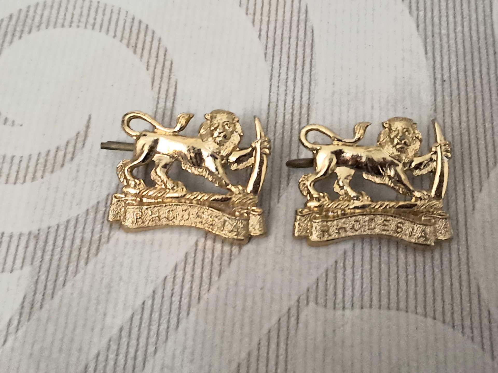 Pair of Rhodesian lion crest cap badges – gilt finish, two-post fastening (pair)