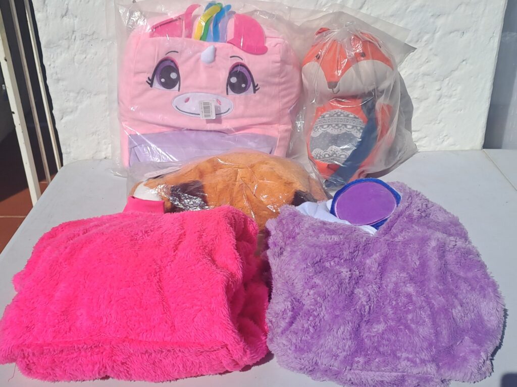 Mixed lot of children’s plush goods — unicorn backpack, fox plush, cushion and two hooded plush sleeping sacks