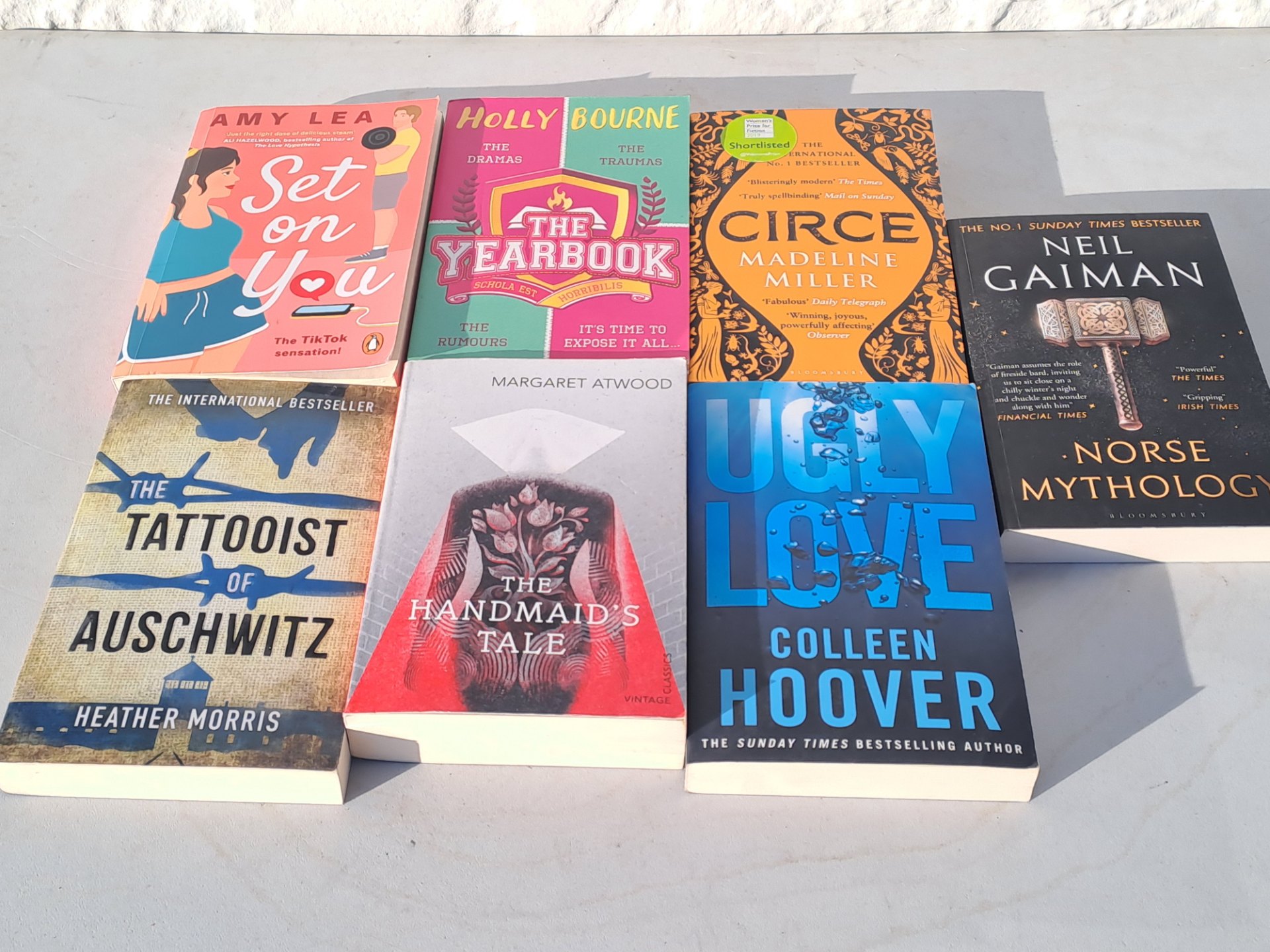 Mixed lot of popular paperback novels — visible titles include Circe, The Handmaid’s Tale, Norse Mythology, The Tattooist of Auschwitz, Ugly Love, The Yearbook, Set On You