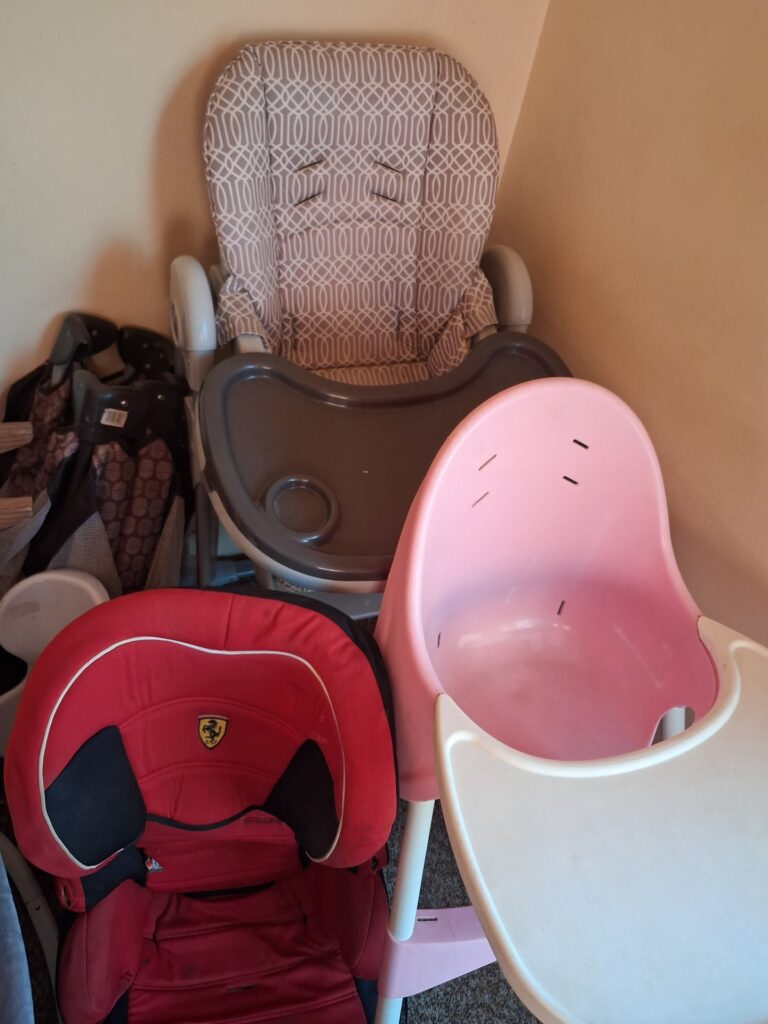 Mixed lot: used baby & child items — red car seat (Ferrari-logo), highchairs, bouncer, wooden rocking horse, easel — untested, sold as pictured