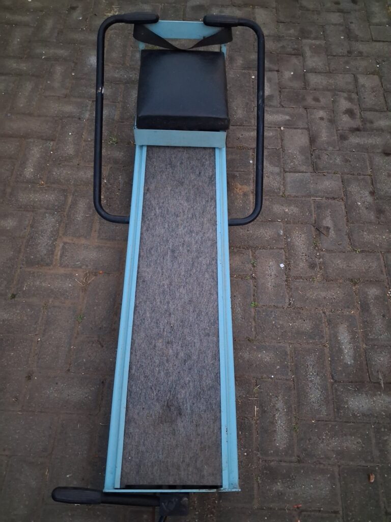 Manual sliding-seat rowing machine — blue frame, padded seat, mechanical bungee (working)