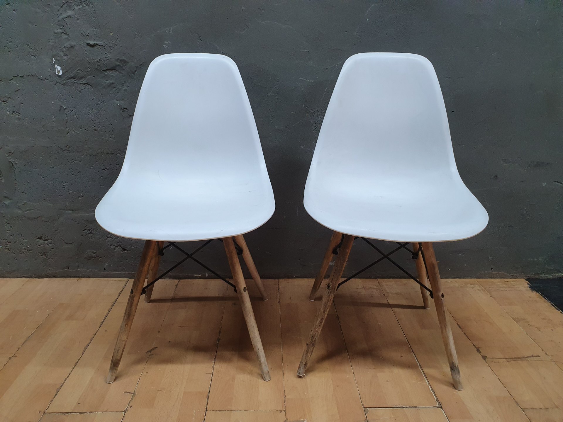 Pair of white plastic shell chairs with wooden legs — used, needs clean