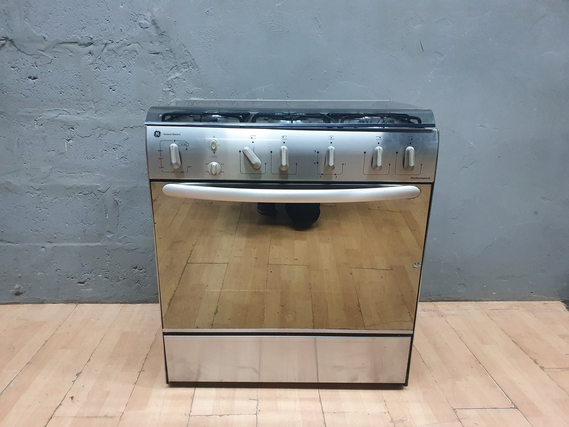 General Electric (GE) 5‑burner LPG freestanding cooker & oven — stainless front, glass lid — working with faults