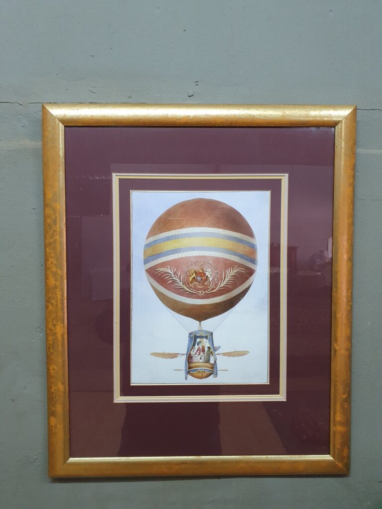 Framed glazed hot‑air balloon print — gilt frame, burgundy double mat (66 x 55 cm)
