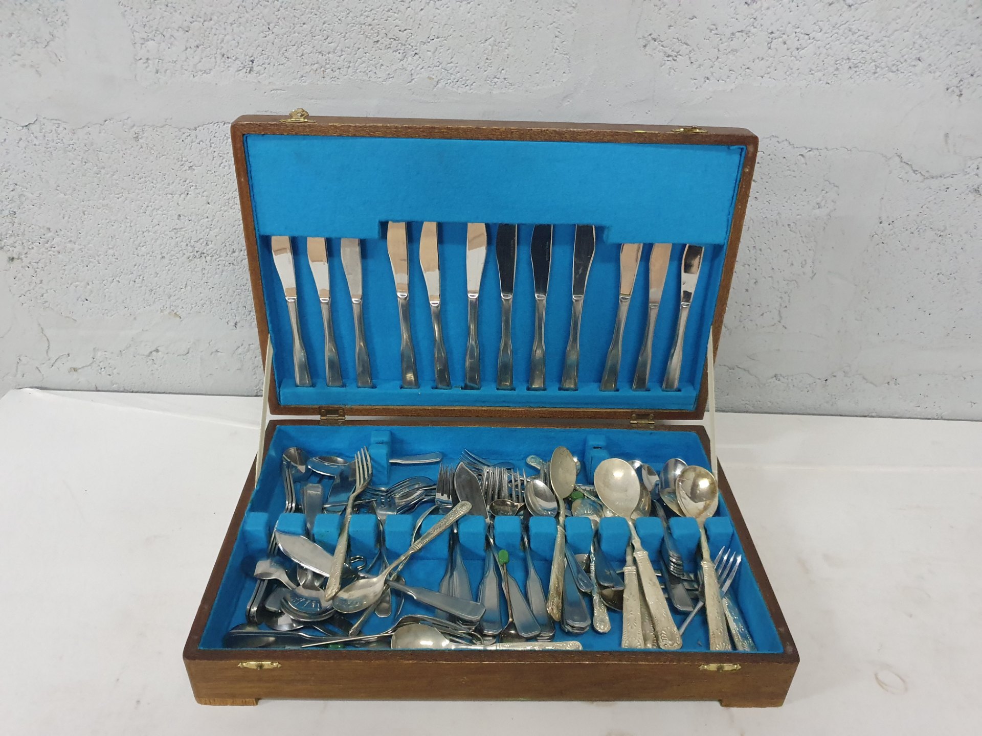 Assorted silver‑plated cutlery in wooden presentation box — mixed patterns, approx. 35 pieces, used