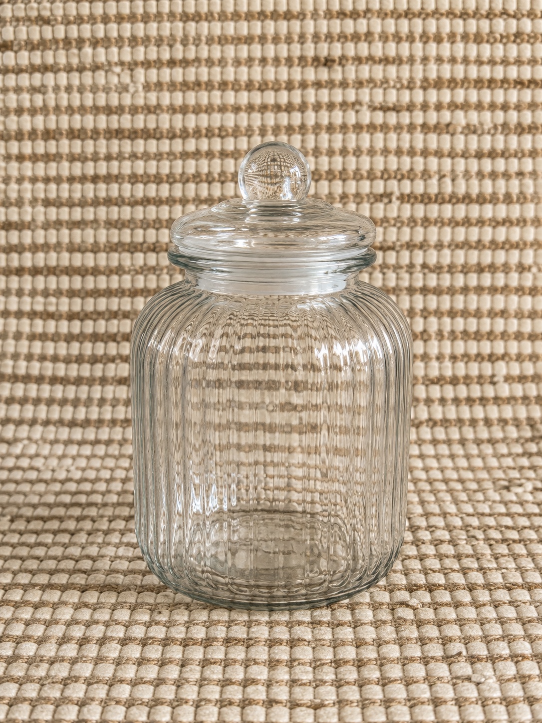 Two ribbed clear glass storage jars with lids + small decorative Roman‑numeral clock (as pictured)