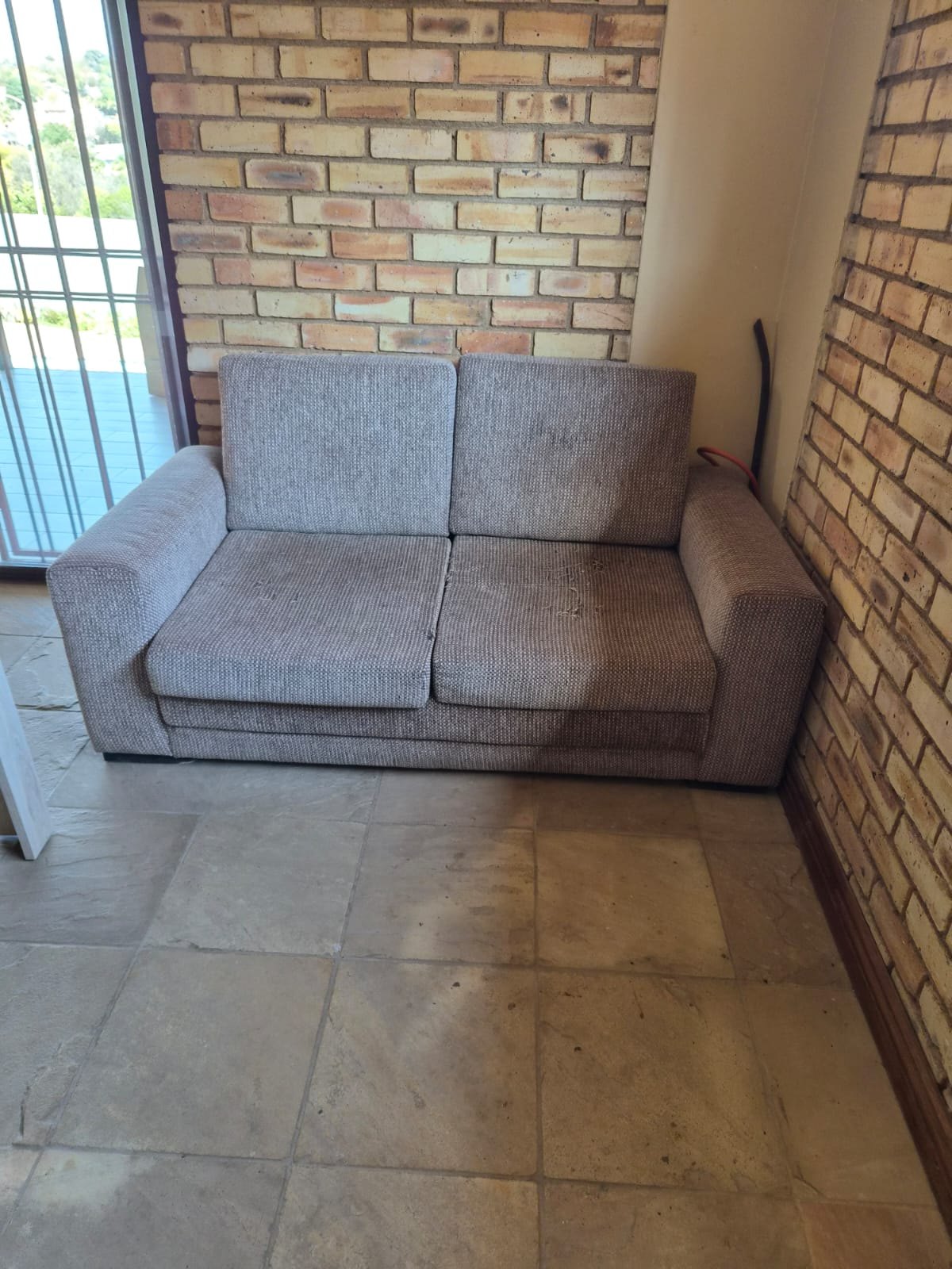 Two‑seater woven fabric sofa / seller describes as brown sleepcouch — used, stained, fabric pulls