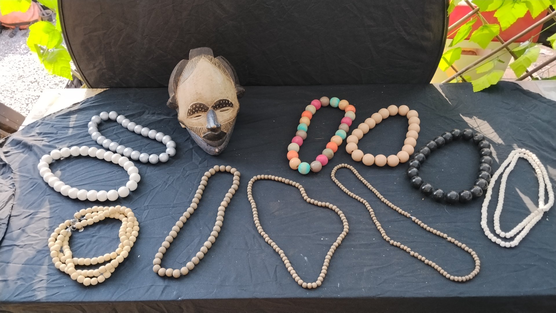 Decorative carved wooden mask on stand with mixed wooden beaded necklaces – display lot