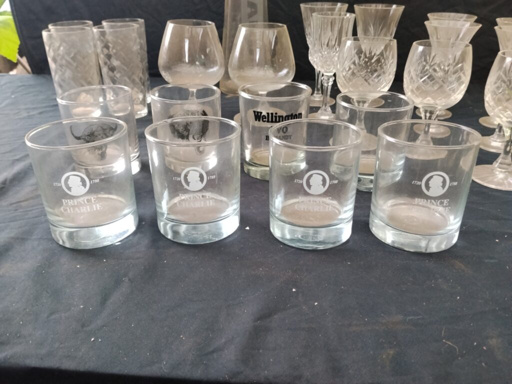 Mixed lot of assorted drinking glasses & stemware — Prince Charlie & Wellington VO tumblers, cut crystal stems, amber-stem goblets + AUDI carafe (used, cloudy/residue)