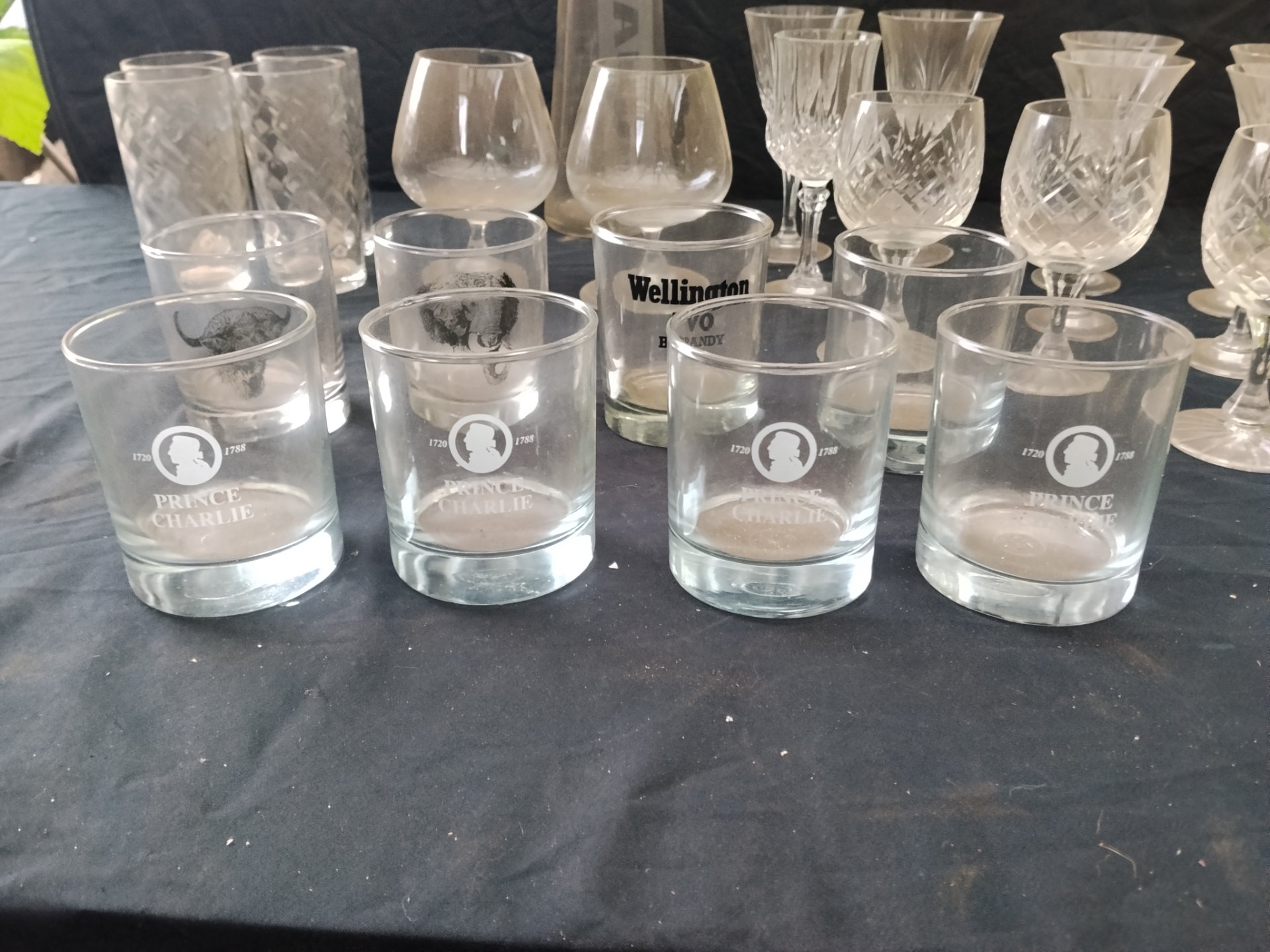 Mixed lot of assorted drinking glasses & stemware — Prince Charlie & Wellington VO tumblers, cut crystal stems, amber-stem goblets + AUDI carafe (used, cloudy/residue)