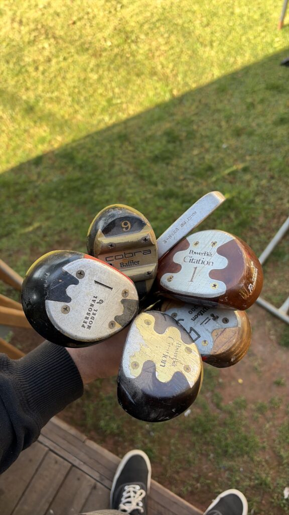 Mixed vintage wooden-headed golf woods (PowerBilt Citation, Cobra Baffler, Wilson) — heavy cosmetic wear