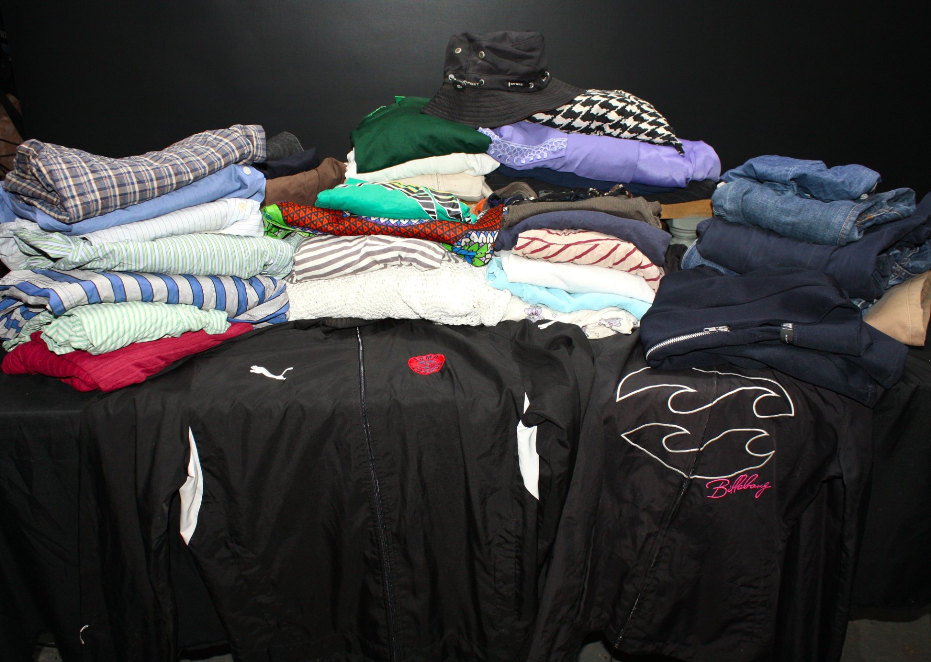 Mixed clothing lot — approx. 25 pieces (shirts, jeans, jumpers, jackets, accessories) — Puma & Billabong visible — sold as‑is