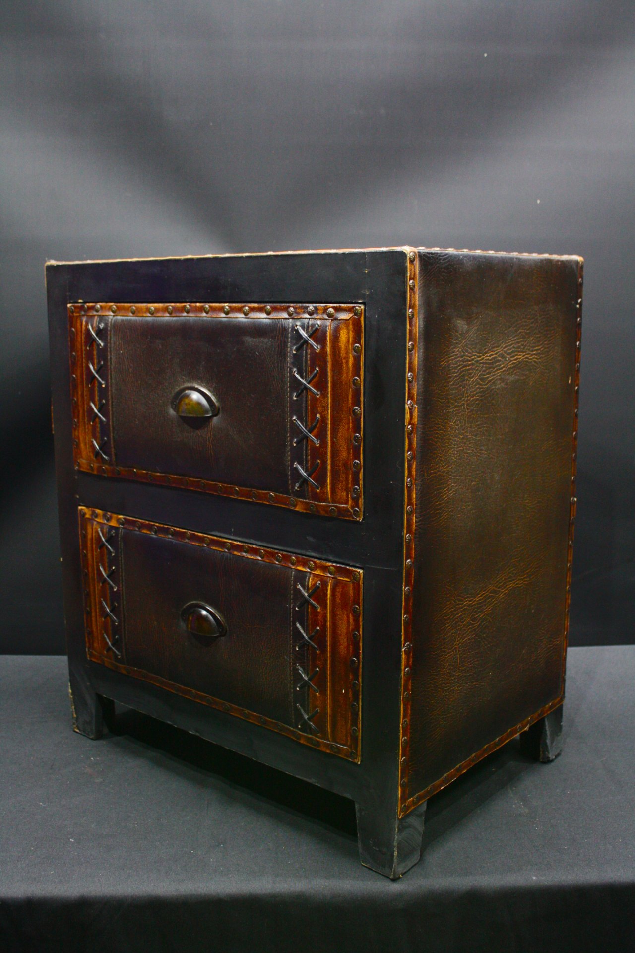 Two-drawer bedside chest with studded leather-faced drawers — worn, drawers slide