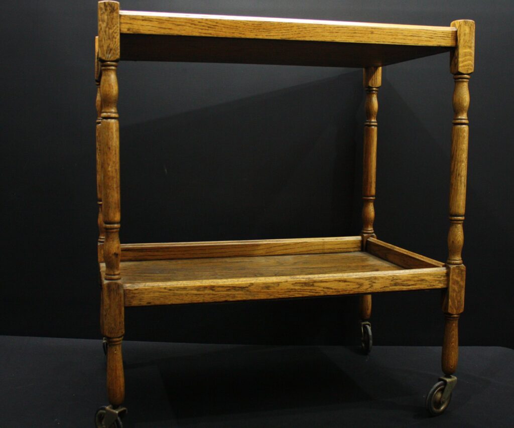 Vintage two-tier wooden serving trolley on swivel castors — turned legs, warm patina