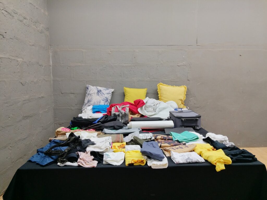 Mixed lot of used clothing, towels, cushions, bags and 2 small suitcases — approx. 60 items