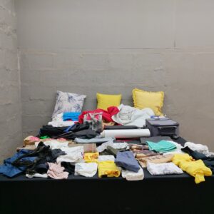 Mixed lot of used clothing, towels, cushions, bags and 2 small suitcases — approx. 60 items