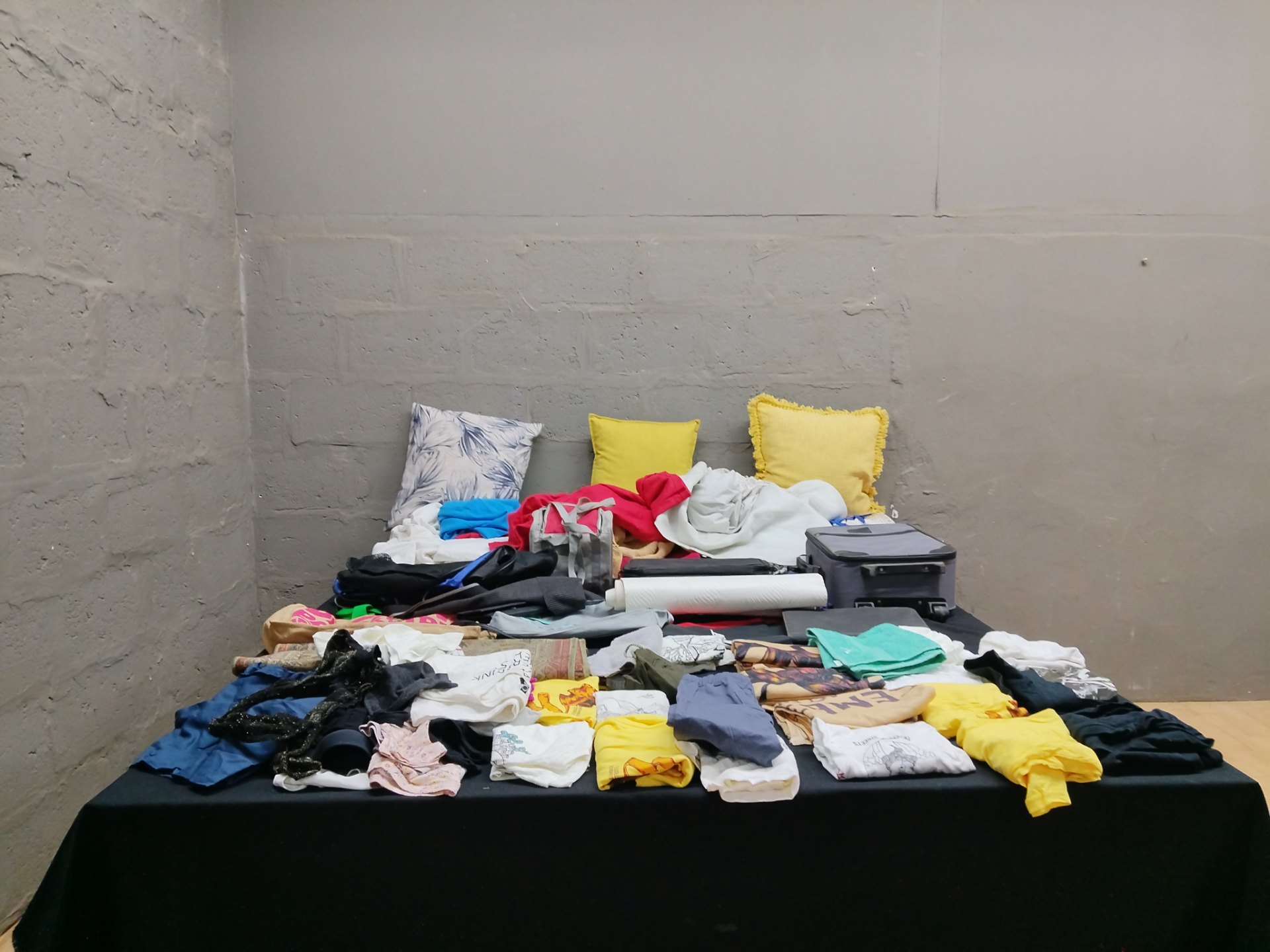 Mixed lot of used clothing, towels, cushions, bags and 2 small suitcases — approx. 60 items