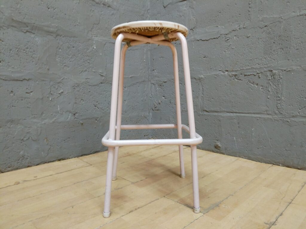 Pale-pink tubular metal bar/bench stool with padded vinyl seat — used, cracked vinyl & frame paint wear