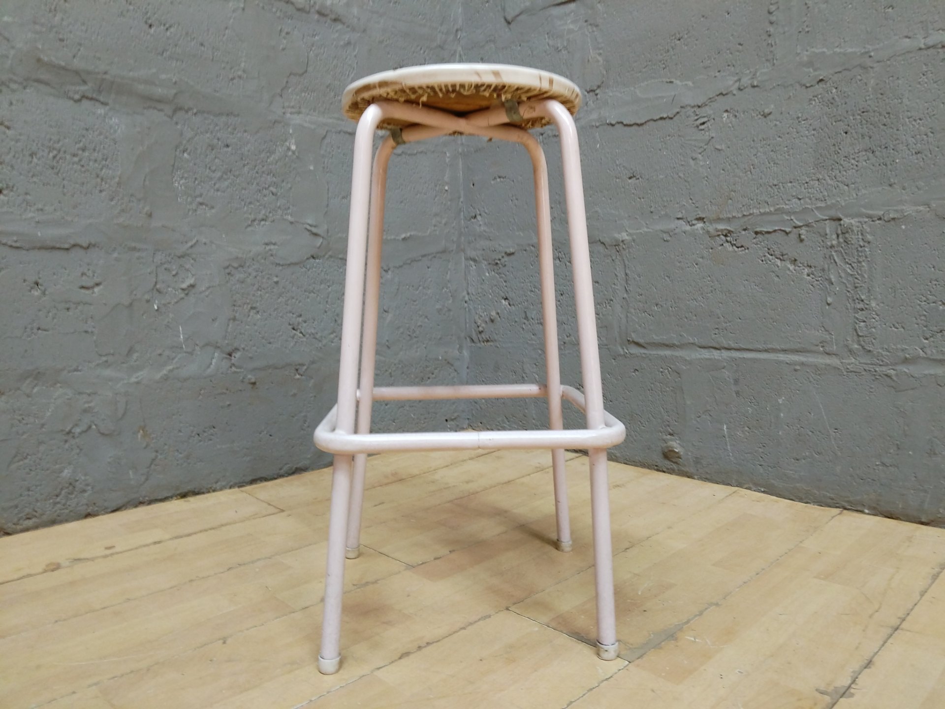 Pale-pink tubular metal bar/bench stool with padded vinyl seat — used, cracked vinyl & frame paint wear